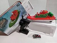 Photo showing the remote control jet ski, black controller, original packaging, and small accessory parts in plastic bag on styrofoam tray.