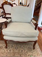 Front view of armchair showing seat cushion, backrest, armrests and carved wooden frame