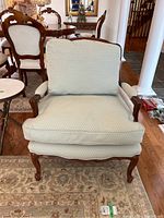 Front view of armchair showing loose seat and back cushions and carved wood base