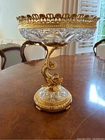 Full side view of the footed crystal bowl with gilt brass dolphin stem and openwork rim