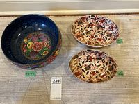 Front and top view of a deep blue Losol Ware Newlyn bowl with colorful floral and fruit pattern around inside base and footed pedestal base, along with two oval Japanese style Imari serving bowls with red, black and cream floral/leaf pattern.