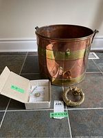 Copper and brass pail with box and brass door knocker on floor