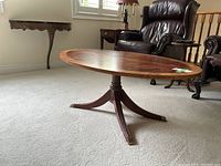 Full profile view of oval Ethan Allen coffee table showing top surface, pedestal base, and surrounding room context.