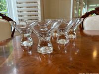 Side angle showing five of the martini glasses on a wooden table, highlighting the bubble bottom bases and conical shape.