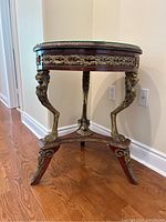 Full side view showing round tabletop, brass legs, and X-shaped stretcher