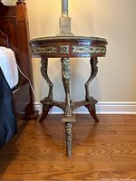 Front view of round side table showing mahogany top, glass surface, brass ormolu skirt, lion leg supports