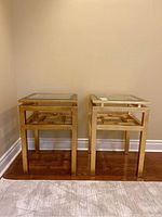 Front corner view of both square gold tables side by side