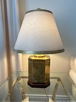 One lamp illuminated on glass side table showing overall design and scale