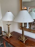 Front view of both lamps on a wooden console table in front of mirror.