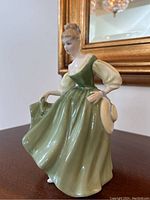 Front side view of Royal Doulton Fair Lady figurine in green dress holding a hat