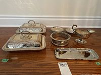 Photo of the full set of silver plated serving dishes and accessories arranged on the floor showing all items in the lot.
