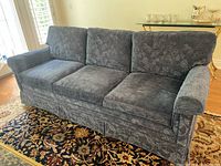 Front angle view showing the floral patterned blue/grey upholstery and loose seat cushions.