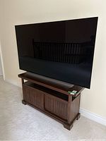 TV stand with dark wood finish and open shelf beneath a mounted TV