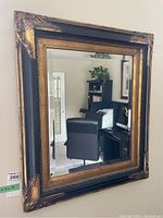 Front view showing the full mirror with black frame detailed with gold highlights and beveled glass.