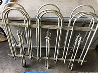 Front view of all four white painted iron fence panels leaning against a wall