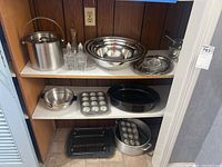 Set of all items on three shelves showing mix of metal bowls, trays, pans, muffin tins and ice bucket