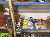 Photo showing a variety of bird feeders, gardening gloves, a metal sun face wall ornament, and packaged mouse catchers arranged on shelves