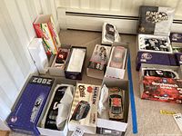 Five boxed collectible model racing cars arranged on floor, showing front and side views of packaging and cars