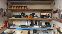 Wide shot of workshop cabinet shelves containing electric drills, drill bits, soldering tools, and assorted hardware items.