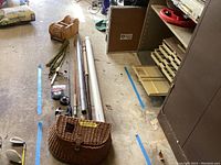 Wide view of all items in lot laid on garage floor showing poles, basket, reels, and spools