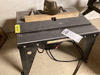 Full view of black Craftsman router table with ribbed work surface and wooden guide clamp on top, showing general condition and setup.