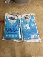 Two unopened bags of Diamond Crystal Solar Naturals salt crystals for water softeners on a concrete floor.
