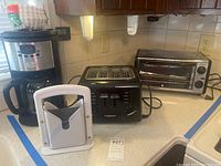 Photo of Cuisinart 4-slice toaster, Krups coffee maker, Krups toaster oven, and bagel slicer on kitchen counter.