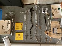 Wide view of all rosaries, pendants, pins, crucifixes laid out including boxes and notes describing markings.