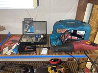 Photo showing Craftsman rotary electric tool kit with accessories, red stapler, blue Makita sander in case, and Chicago Electric saw on shelf