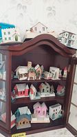 Full cabinet display of vintage paper houses of various colors and styles