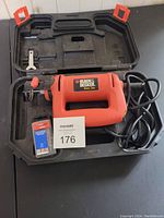 Black & Decker rotary saw with power cord inside molded hard plastic carrying case. Includes two packs of spare blades and a wrench tool.