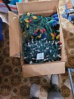 Box filled with several tangled strands of Christmas string lights with different shaped and colored bulbs, tested working at time of auction.