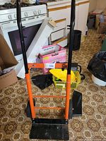 Front view of the dolly showing upright orange frame, handles and black base plate.
