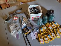 Wide view of assorted hardware containers, tools, and glass insulators on table