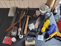 Overview of entire lot showing hammer, square, hand shears, hand saw, soldering paste, nails, vice, sand blaster, yellow abrasive discs, gloves and miscellaneous items