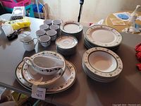 Full view of holiday themed dinnerware including plates, bowls, cups, saucers, platter, vegetable bowl, creamer, and gravy boat arranged on a table