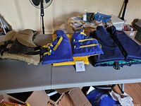 Four personal floatation devices laid out on a table showing front view and size variety