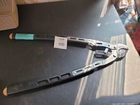 Pair of ratcheting pruning shears with long metal handles and black grips, laid open on a dark table.