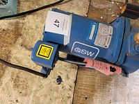 Blue GE motor for shallow well jet pump with attached power cord and on a wooden surface.