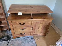 Full view of wooden TV stand showing three drawers on the left and cupboard door on the right, slight damage visible on top surface