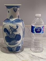 Blue and white porcelain vase photographed next to water bottle for size reference.