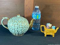 Two teapots displayed side by side with a water bottle for size reference