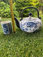 Teapot and mug displayed outdoors on grass with measuring tape showing approximate height of 12 cm for teapot and 6.5 cm for mug.