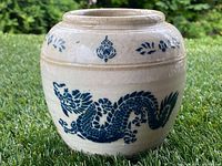 Front view of the white pottery vase with a detailed blue hand-painted dragon wrapping around the body and a decorative border near the neck.