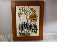 Frontal image of the framed embroidered birch trees scene showing the full artwork and wooden frame.