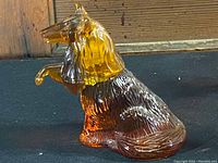 Amber and brown glass dog figurine sitting with raised paw, unbroken shown sitting upright
