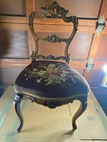 Front and angled side view of Victorian solid mahogany chair showing carved backrest and needlepoint floral upholstered seat.