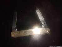 Gold filled folding pocket watch fob with two stainless steel blades, one larger and one smaller, both partially open and showing some wear.