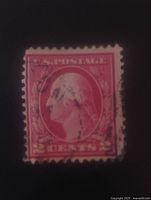 Close-up photo of 2 cent bright red George Washington postage stamp with visible perforation and cancellation marks.