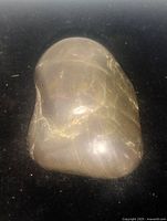 Polished brown mineral gemstone with natural yellowish veining on a black background